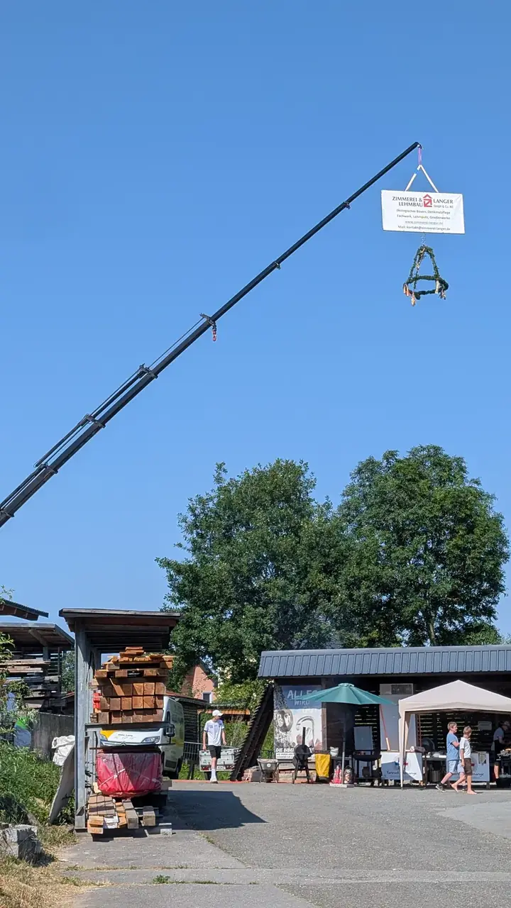 Kranausleger mit Firmenbanner und Richtkranz über dem Festgelände